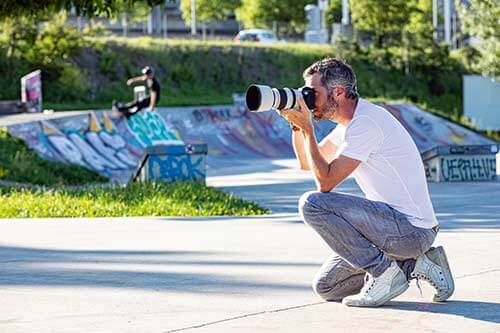 Side view of a photographer at work in front of a skater facility