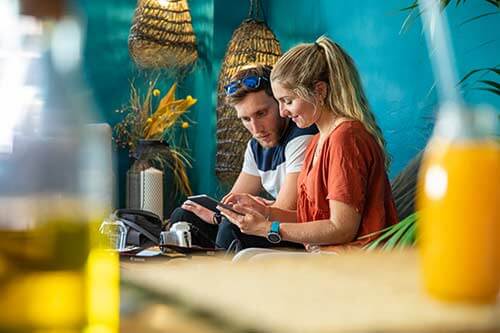 Two tourists sitting in a bar looking at a smartphone
