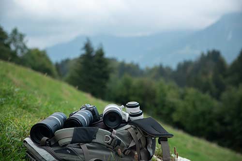 Canon cameras and lenses on a backpack on a meadow on a mountain slope